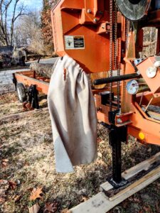 Woodchipper bag hanging from the outfeed on the sawmill. 